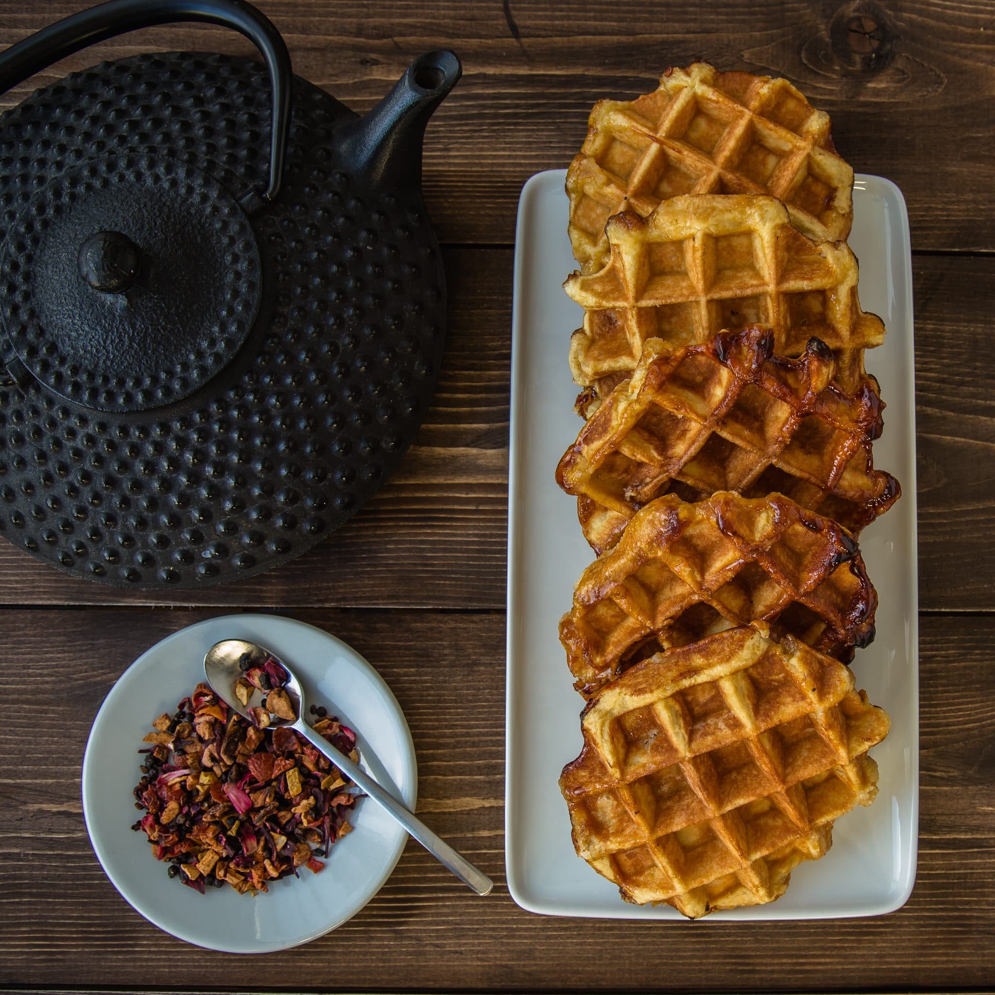 Versgebakken wafels naast een gietijzeren theepot