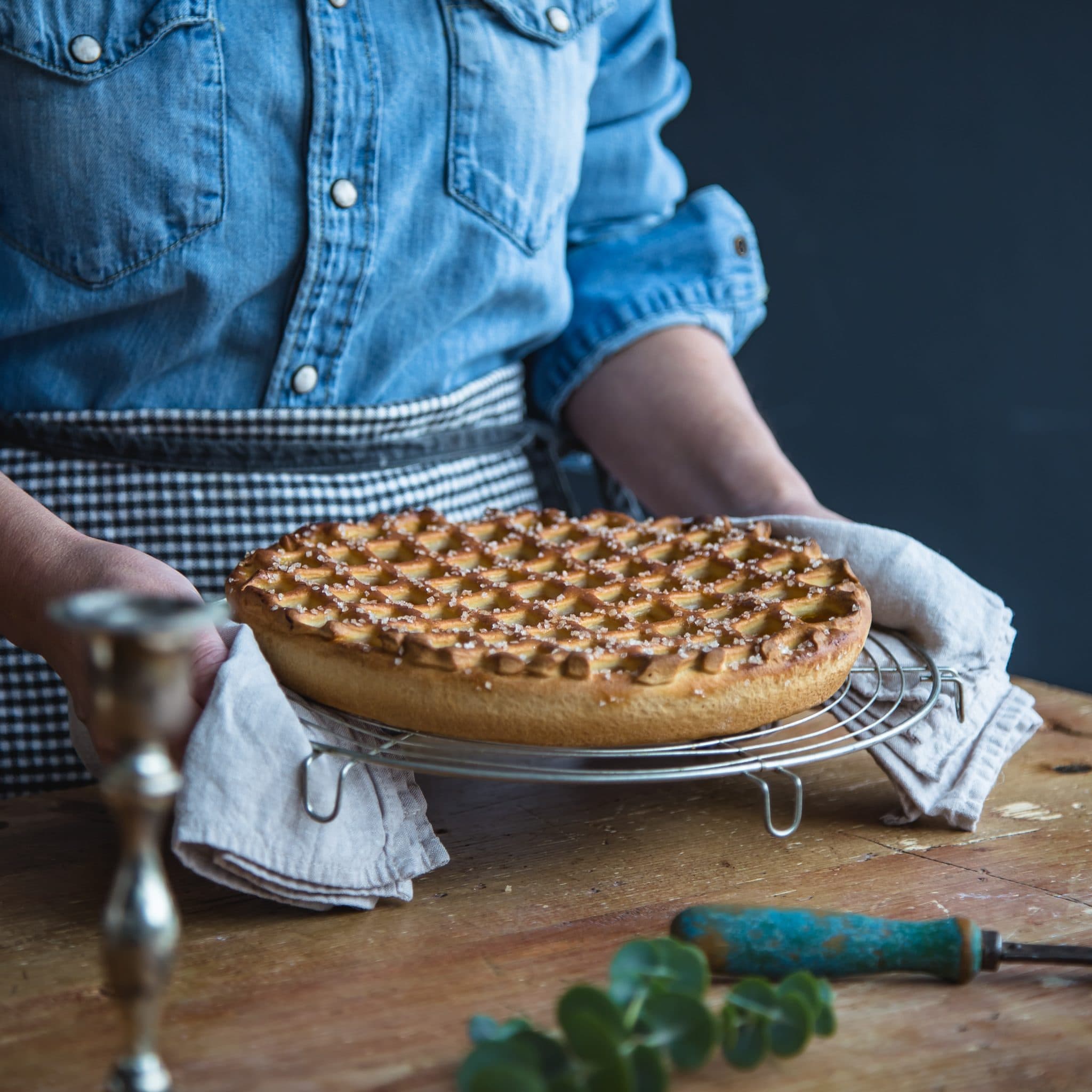 Bakker met een Limburgse vlaai met roosterpatroon in de handen